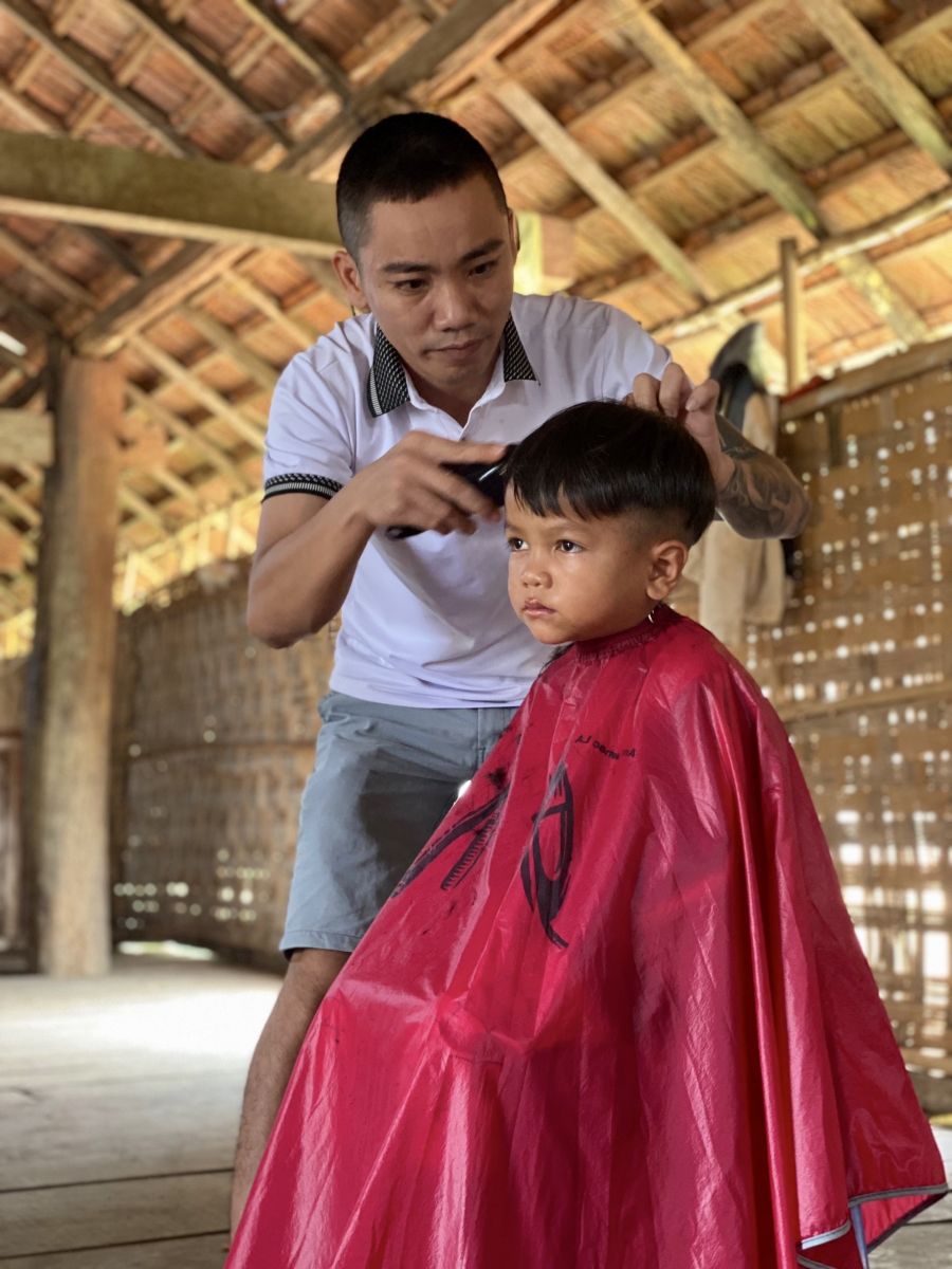 A person cutting a child's hair  Description automatically generated